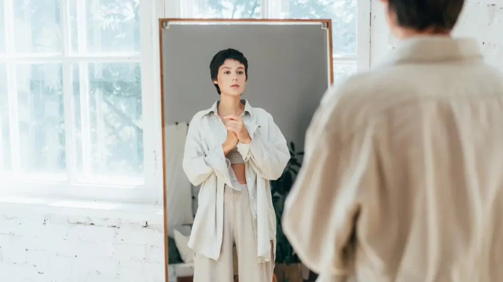 Mirror with individual contemplating transgender body image