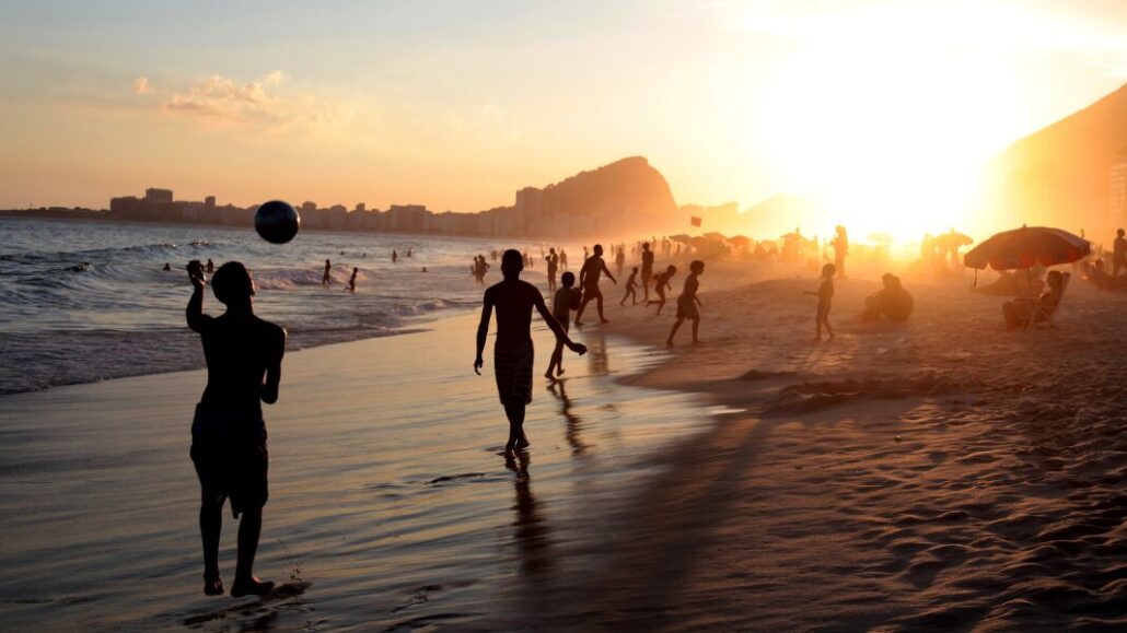 bodies walking along beach at sunset