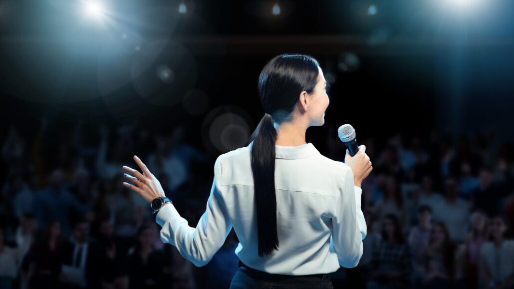 woman in front of crowd public speaking